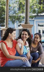 Three young women sitting together and smiling, Old San Juan, San Juan, Puerto Rico