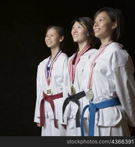 Three young women standing with their medals and smiling