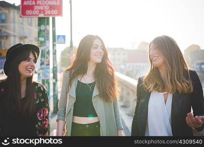 Three young women strolling and chatting in city
