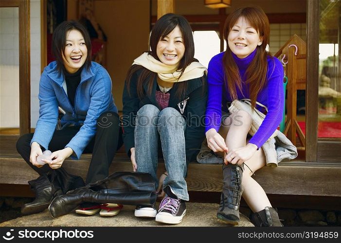 Three young women tying their shoe laces
