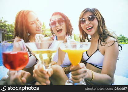 three younger asian woman happiness drinking beverage in waer swimming pool