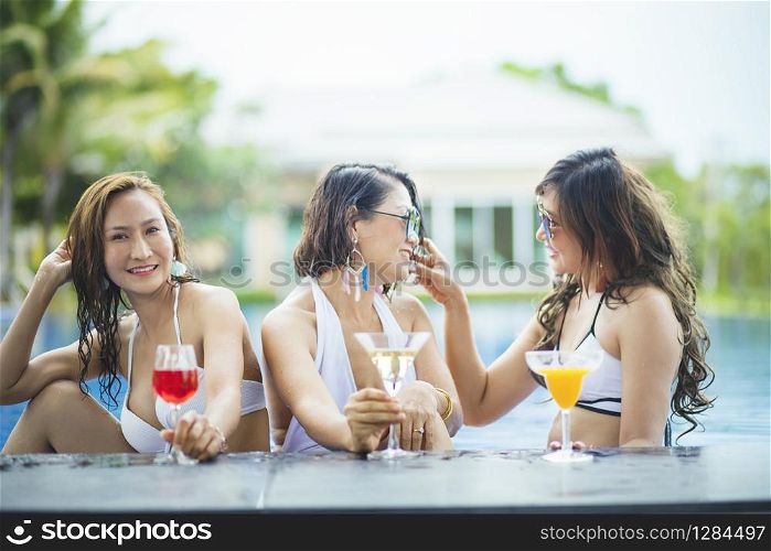 three younger asian woman happiness drinking beverage in waer swimming pool