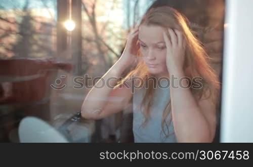Through the window warm portrait of girl enjoying her hair. Beautiful back light.
