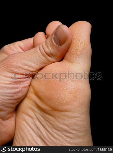 Thumb pressure on big toe massage on dry skin isolated towards black
