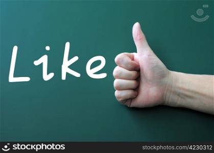 Thumb up gesture on a blackboard background with the word Like written in white chalk