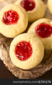 Thumbprint Christmas cookies filled with strawberry jam, photographed with natural light (Selective Focus, Focus diagonally through the middle of the first cookie)