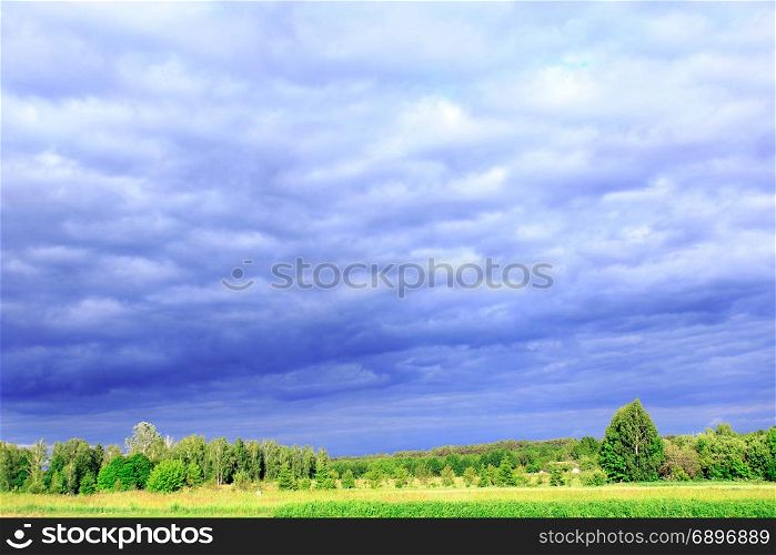 thundercloud clouds under the forest and land. landscape with dark thundercloud clouds under the forest and land