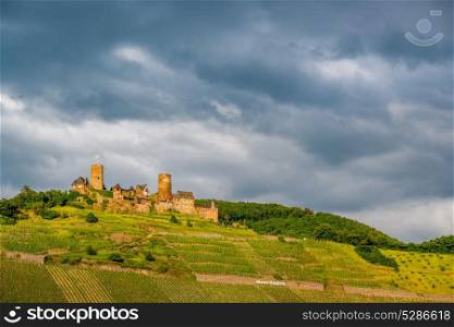 Thurant Castle and vineyards above Moselle river and under dramatic sky near Alken, Germany. Built between 1198 and 1206.