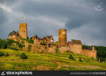 Thurant Castle and vineyards above Moselle river and under dramatic sky near Alken, Germany. Built between 1198 and 1206.
