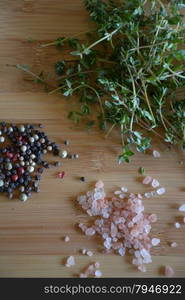 thyme, pink salt, and peppercorns on a wood cutting board