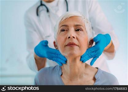 Thyroid gland control. Endocrinology doctor examining senior woman at a clinic.. Thyroid Gland Control. Endocrinology Doctor Examining Senior Woman at Clinic.