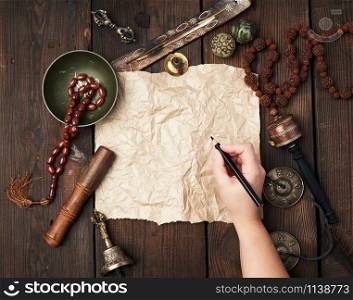 tibetan religious objects for meditation and alternative medicine, empty brown sheet of paper on a brown wooden background, top view, copy space
