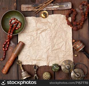 tibetan religious objects for meditation and alternative medicine, empty brown sheet of paper on a brown wooden background, top view