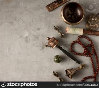 Tibetan singing copper bowl with a wooden clapper on a gray cement background, objects for meditation and alternative medicine, top view, copy space