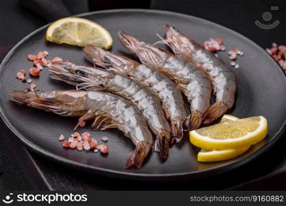 Tiger prawn or langoustine raw with spices and salt on a wooden cutting board on a dark concrete background