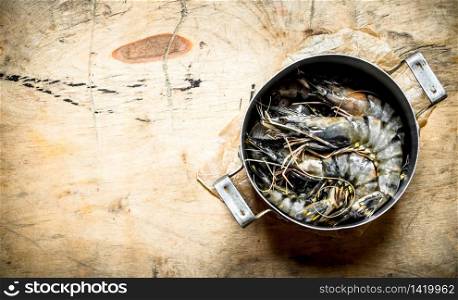 Tiger prawns in an old saucepan. On wooden background .. Tiger prawns in an old saucepan.
