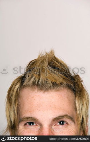 Tight crop of young male with interesting hairstyle.