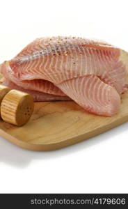 tilapia fillets on a cutting board with spices