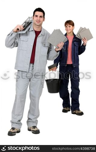 Tile fitters holding up their building supplies and tools
