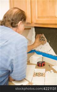 Tile setter uses spacers to carefully apply tiles to the wall.
