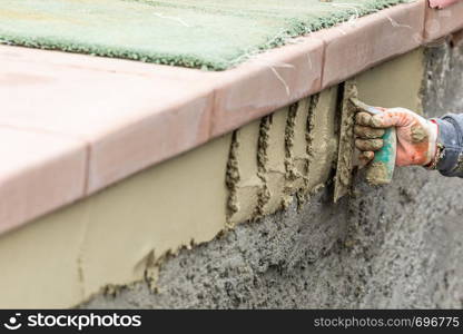 Tile Worker Applying Cement with Trowel at Pool Construction Site.