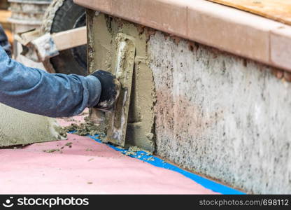 Tile Worker Applying Cement with Trowel at Pool Construction Site.