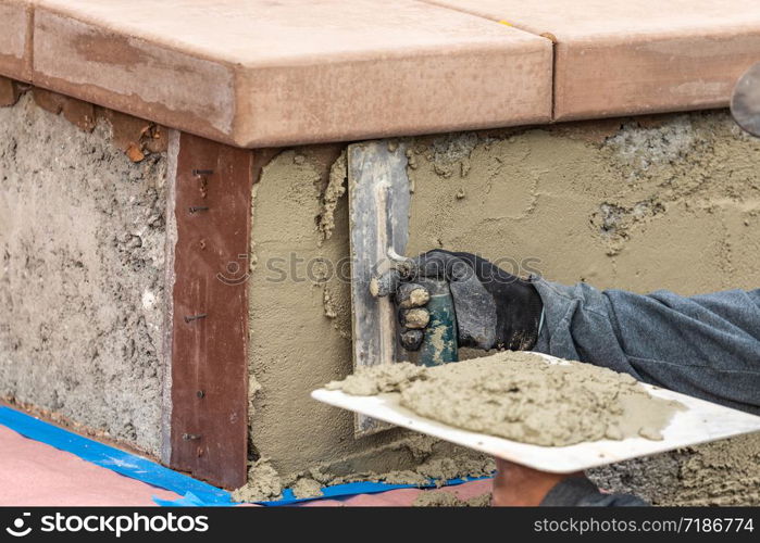 Tile Worker Applying Cement with Trowel at Pool Construction Site.