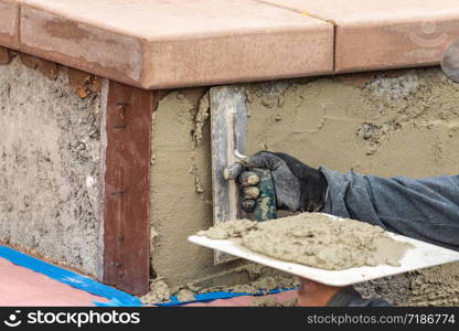 Tile Worker Applying Cement with Trowel at Pool Construction Site.