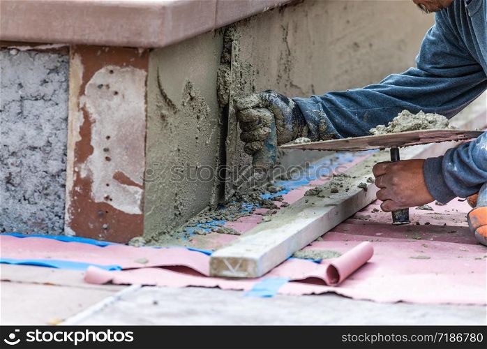 Tile Worker Applying Cement with Trowel at Pool Construction Site.
