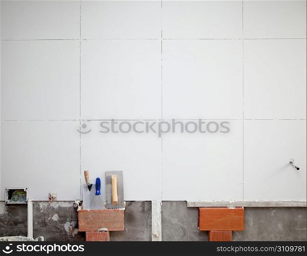 tiles white wall contruction with trowels tools and bricks