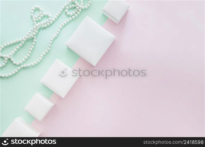 tilt row different white boxes with pearls necklace pastel background