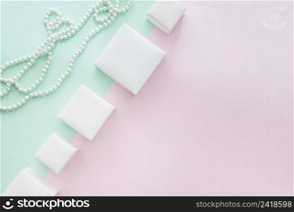 tilt row different white boxes with pearls necklace pastel background