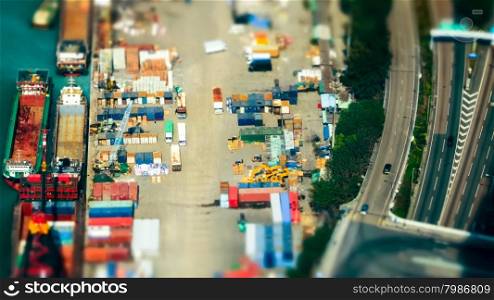 Tilt shift blur effect. Aerial view cargo ships loaded by crane with cargo containers at a busy port terminal. Hong Kong