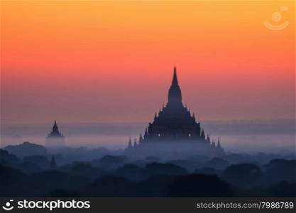 Tilt Shift blur effect. Amazing misty sunrise colors and silhouette of ancient Myauk Guni Pagoda. Architecture of ancient Buddhist Temples at Bagan Kingdom. Myanmar (Burma) travel destinations