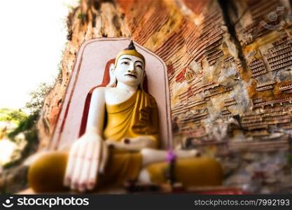 Tilt shift blur effect. Amazing view of lot Buddhas statues and religious carving on limestone rock in sacred Kaw Goon cave. Hpa-An, Myanmar (Burma) travel landscapes and destinations