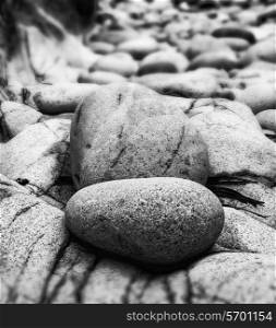 Tilt shift effect image with shallow depth of field textured rocks on beach black and white