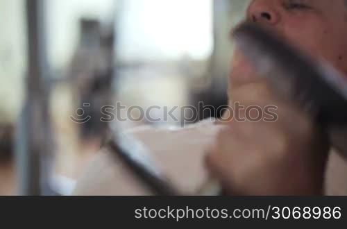 Tilt shot of a mature man working out hard with dumb-bells