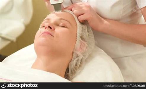 Tilt shot of a woman getting ultrasonic face treatment at beauty spa