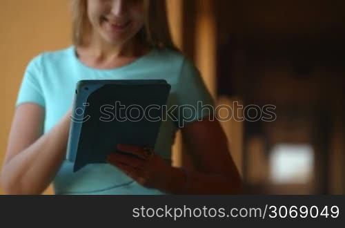 Tilt shot of a woman using a touch pad standing by the window in the hall