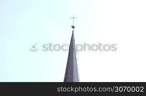 Tilt shot of Catholic church with high cone roof and big green trees nearby. Estonia, Europe