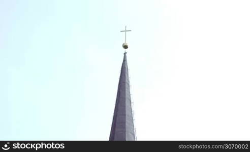 Tilt shot of Catholic church with high cone roof and big green trees nearby. Estonia, Europe