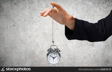 Time concept. Close up of businessman holding clock on rope