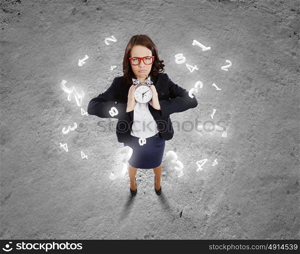 Time concept. Top view of upset businesswoman holding alarm clock