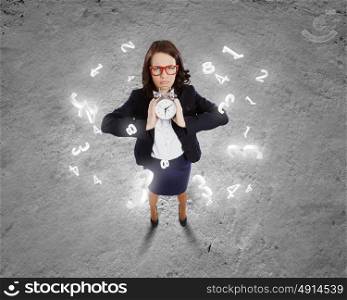 Time concept. Top view of upset businesswoman holding alarm clock