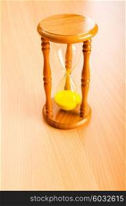 Time concept with hourglass on wooden background