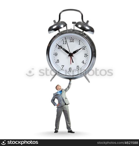 Time concept. Young strong businessman lifting huge alarm clock above head