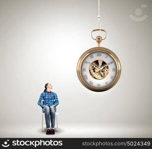 Time concept. Young woman sitting on chair and looking at pocket watch