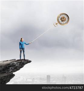 Time concept. Young woman standing on edge of rock with pocket watch