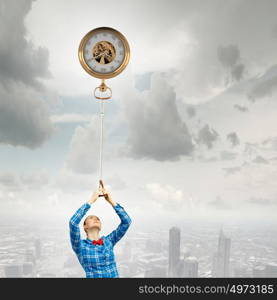 Time concept. Young woman standing on edge of rock with pocket watch