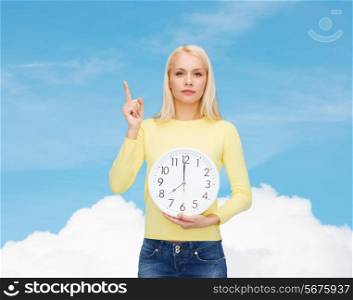 time, education and people concept - serious young woman with wall clock showing 8 and finger up